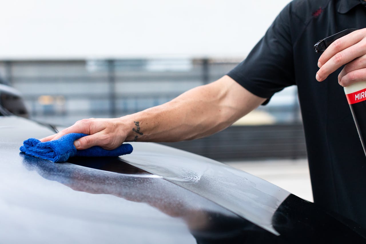 services-04 Close-up of hand cleaning car with cloth and spray bottle for maintenance.